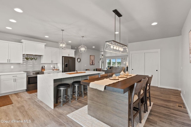 kitchen featuring white cabinets, light wood finished floors, stainless steel appliances, tasteful backsplash, and a center island