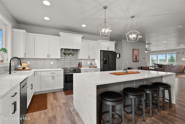 kitchen featuring a kitchen bar, wood finished floors, stainless steel appliances, a kitchen island, and an inviting chandelier
