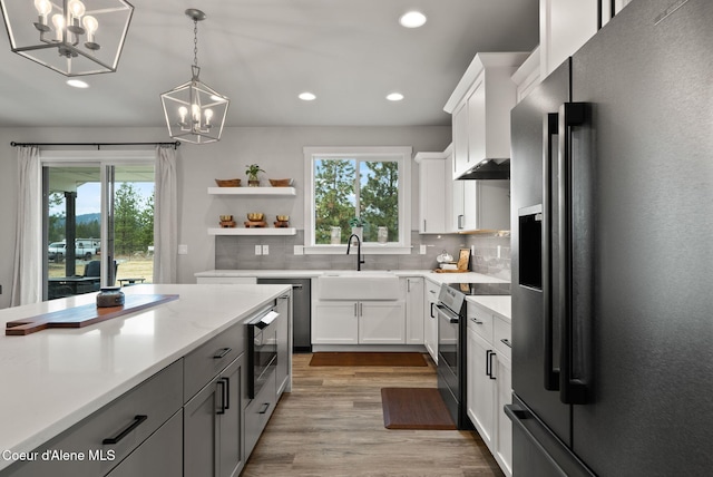 kitchen with tasteful backsplash, a chandelier, refrigerator with ice dispenser, black / electric stove, and a sink