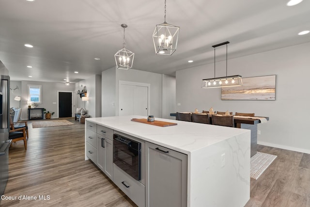 kitchen featuring light stone countertops, a notable chandelier, light wood finished floors, and recessed lighting
