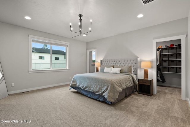 bedroom featuring light carpet, recessed lighting, a walk in closet, and a chandelier