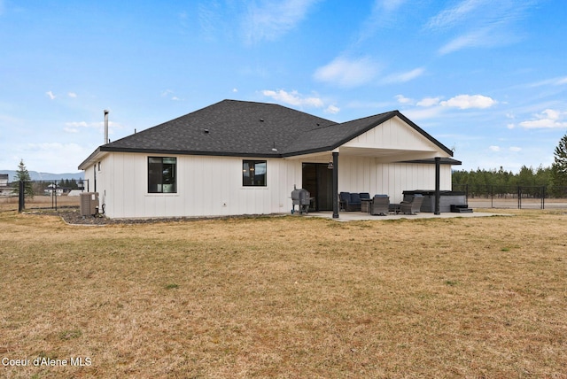 rear view of property featuring fence, a lawn, a patio area, and a hot tub
