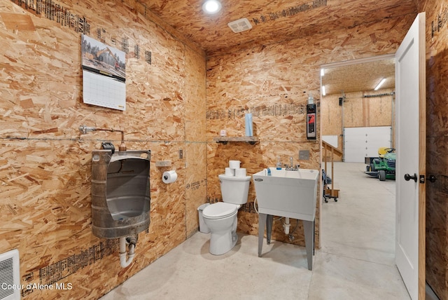 bathroom featuring a sink, concrete floors, and toilet