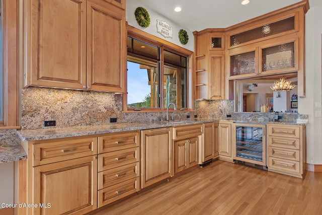 kitchen with sink, an inviting chandelier, backsplash, wine cooler, and light hardwood / wood-style floors