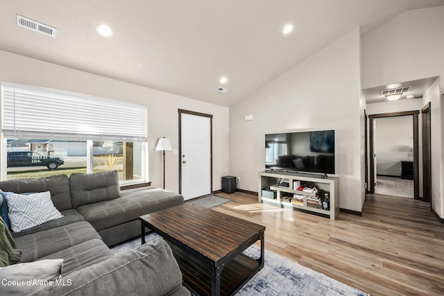 living room with hardwood / wood-style floors and high vaulted ceiling