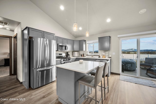 kitchen with a kitchen bar, decorative light fixtures, appliances with stainless steel finishes, a mountain view, and a kitchen island