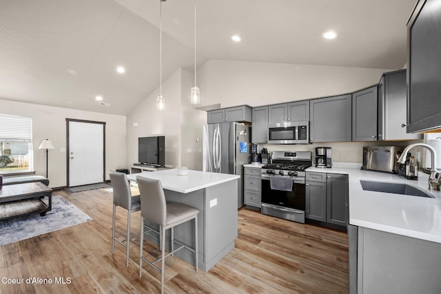 kitchen featuring pendant lighting, sink, gray cabinetry, stainless steel appliances, and a center island