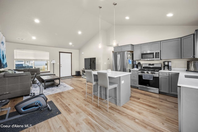 kitchen with gray cabinets, appliances with stainless steel finishes, a breakfast bar, and pendant lighting