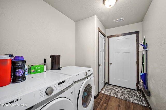 laundry area featuring dark hardwood / wood-style flooring, a textured ceiling, and washing machine and clothes dryer