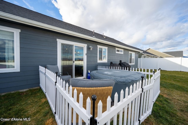 rear view of property featuring a yard and a hot tub