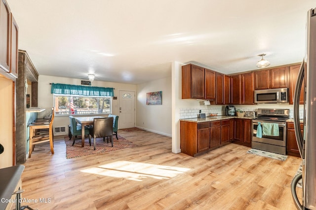 kitchen featuring decorative backsplash, stainless steel appliances, and light wood-type flooring