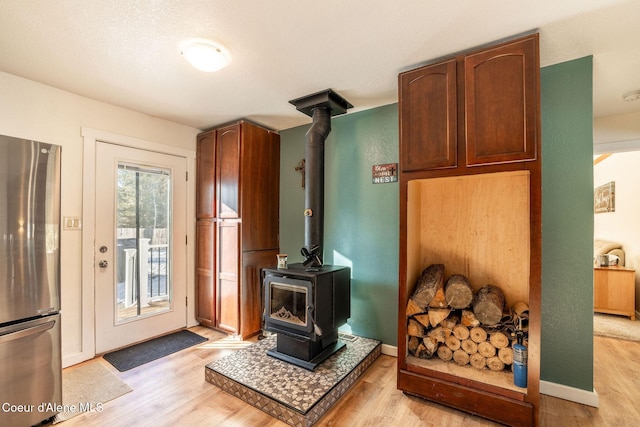 interior space with light hardwood / wood-style floors and a wood stove