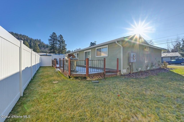 rear view of property featuring a deck and a lawn