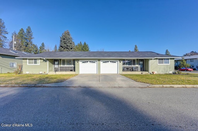 ranch-style home featuring a garage, covered porch, and a front lawn