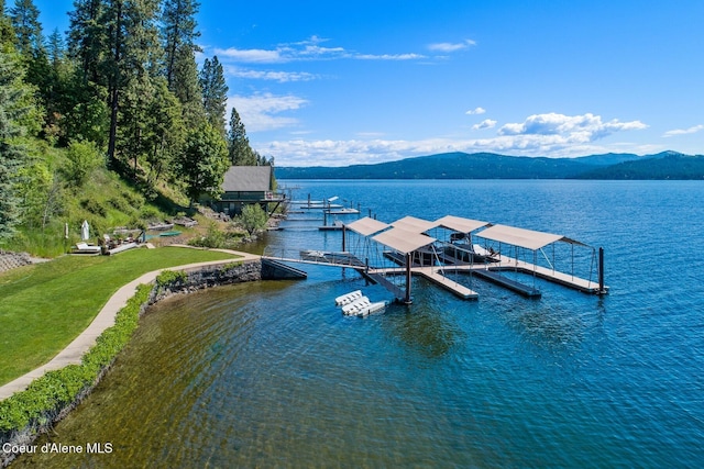 dock area with a water and mountain view and a yard