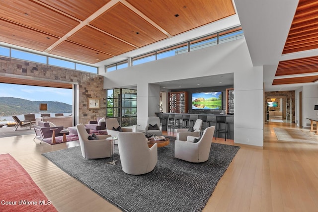 living room with a high ceiling, a mountain view, light wood-type flooring, and wood ceiling