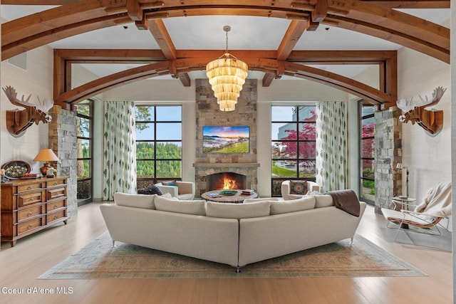 living room with beamed ceiling, a stone fireplace, high vaulted ceiling, and light wood-type flooring