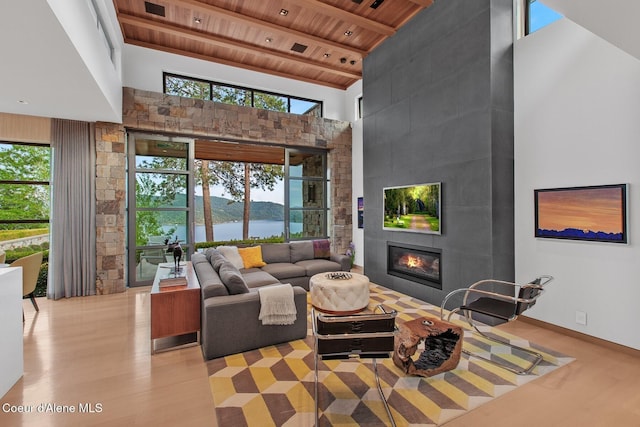 living room featuring wood ceiling, plenty of natural light, a high ceiling, and a water view