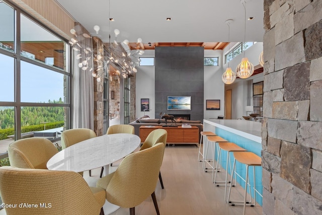 dining room with a fireplace, light hardwood / wood-style flooring, and a high ceiling