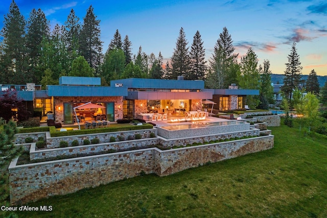 back house at dusk featuring outdoor lounge area, a yard, and a patio area