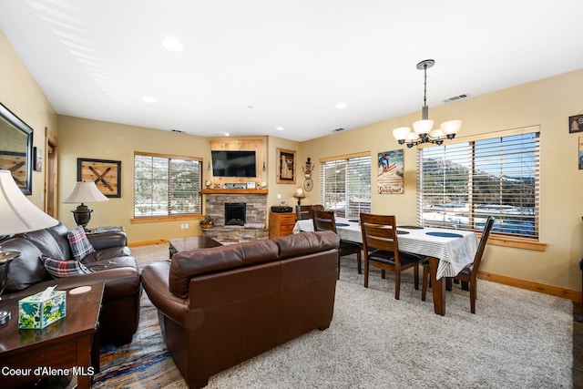 living room featuring a stone fireplace and a notable chandelier