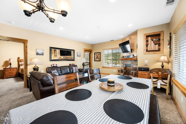 carpeted dining room featuring a notable chandelier and a fireplace