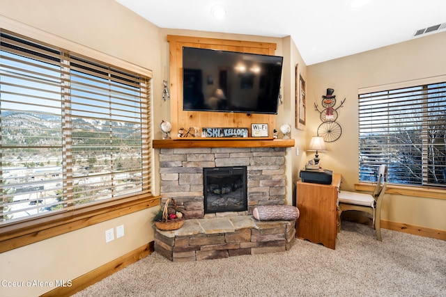 carpeted living room featuring a stone fireplace