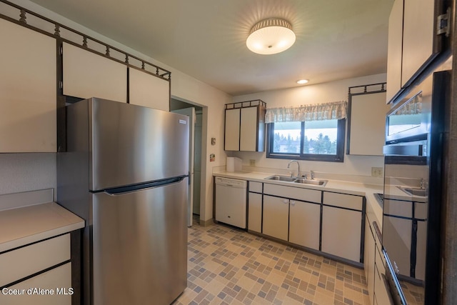 kitchen featuring stainless steel refrigerator, white cabinetry, dishwasher, and sink