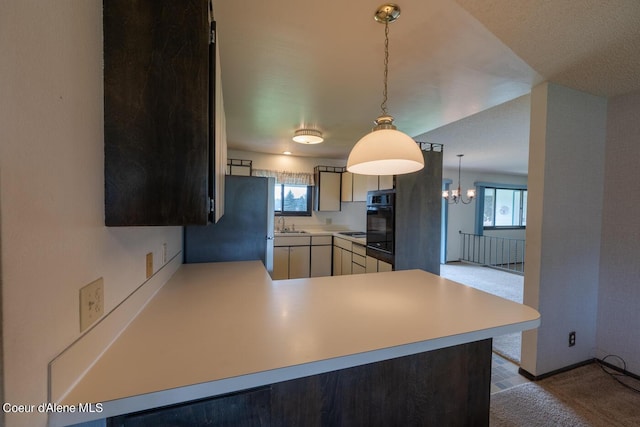 kitchen with a wealth of natural light, black oven, kitchen peninsula, and stainless steel refrigerator