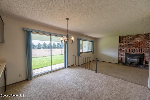 unfurnished living room featuring a notable chandelier, a fireplace, a textured ceiling, and carpet flooring