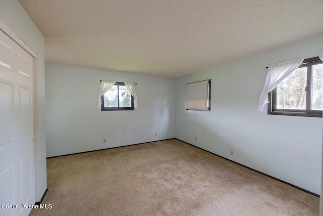 carpeted empty room with a textured ceiling