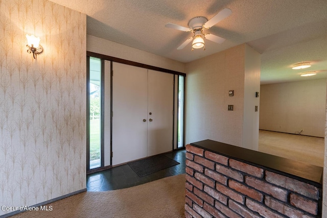 entrance foyer with carpet, a wealth of natural light, and a textured ceiling