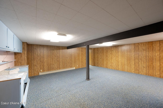 basement with a baseboard heating unit, carpet floors, and wood walls