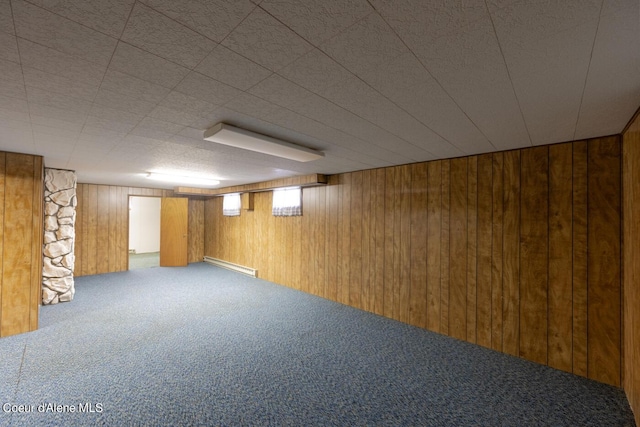 basement featuring carpet, a baseboard heating unit, and wood walls