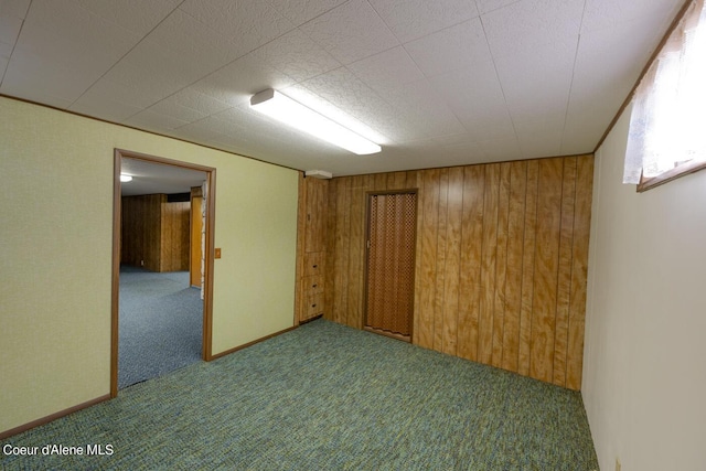 carpeted empty room with wood walls