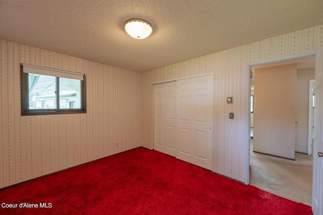 unfurnished bedroom featuring carpet flooring, a textured ceiling, and a closet