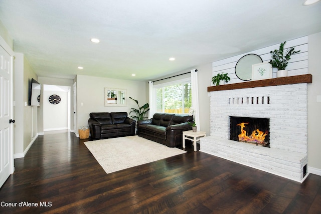 living room with dark hardwood / wood-style flooring and a brick fireplace