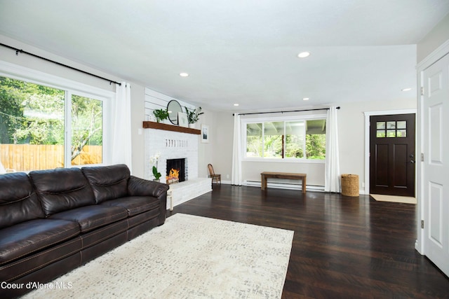 living room with a brick fireplace, dark hardwood / wood-style floors, and a baseboard radiator