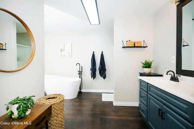 bathroom featuring hardwood / wood-style flooring, vanity, and a tub to relax in