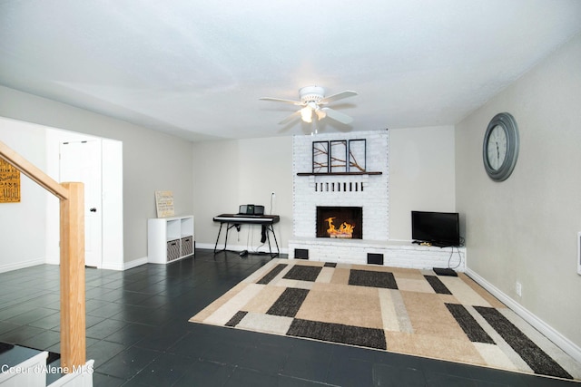 living room with a fireplace, dark tile patterned flooring, and ceiling fan