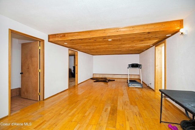 exercise room featuring light wood-type flooring and wooden ceiling
