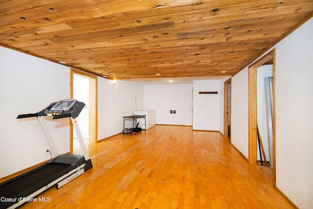 exercise room with light hardwood / wood-style floors and wooden ceiling