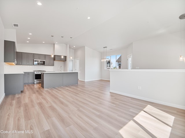 kitchen with decorative light fixtures, a center island, gray cabinets, a notable chandelier, and stainless steel appliances