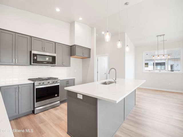 kitchen with stainless steel appliances, gray cabinets, sink, and hanging light fixtures