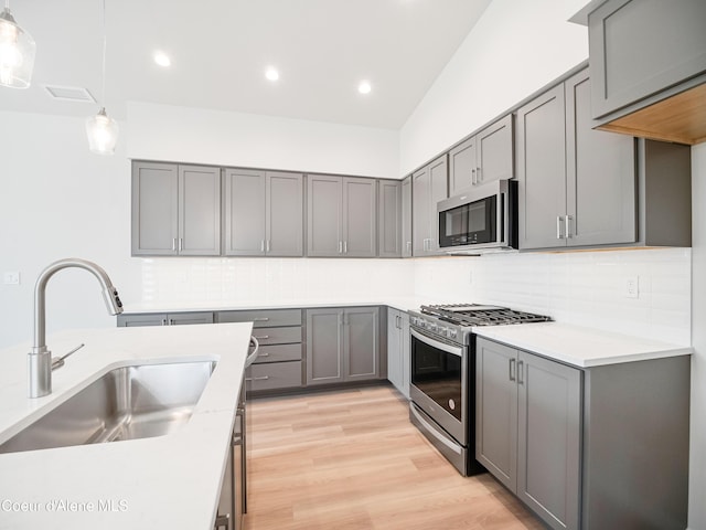 kitchen with appliances with stainless steel finishes, gray cabinetry, pendant lighting, and sink