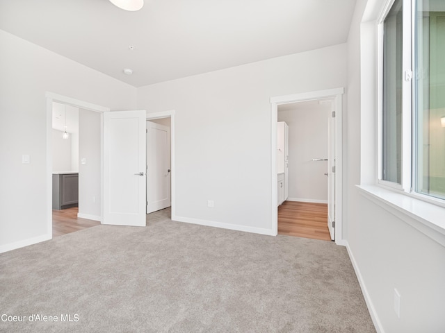 unfurnished bedroom featuring light colored carpet and ensuite bathroom