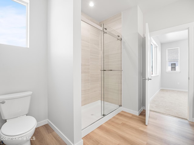 bathroom with hardwood / wood-style flooring, toilet, and an enclosed shower