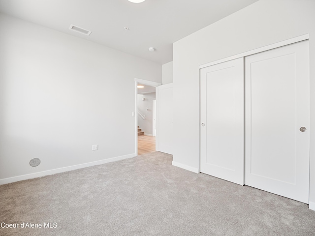 unfurnished bedroom with light colored carpet and a closet