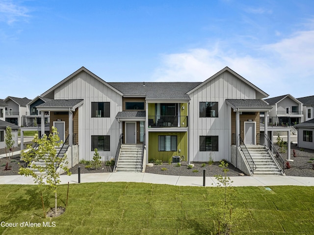 view of front of property with central AC, a balcony, and a front yard