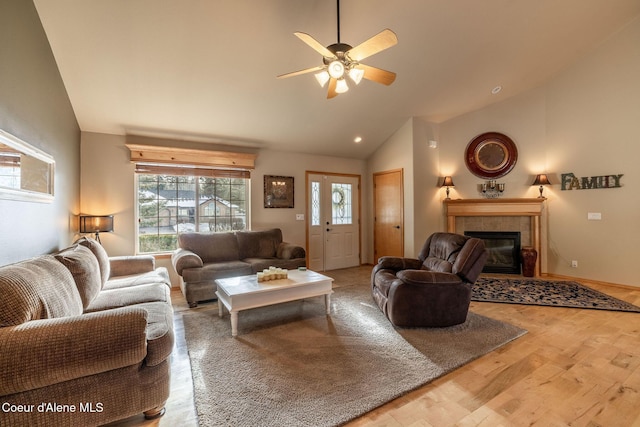 living room with hardwood / wood-style floors, high vaulted ceiling, a tile fireplace, and ceiling fan